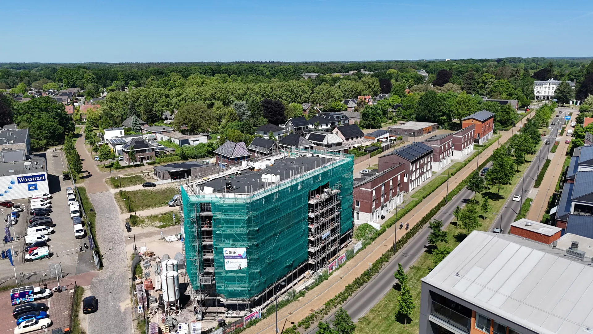 Bovenaanzicht van een appartementengebouw dat in de steigers staat met een groen bouwdoek er omheen