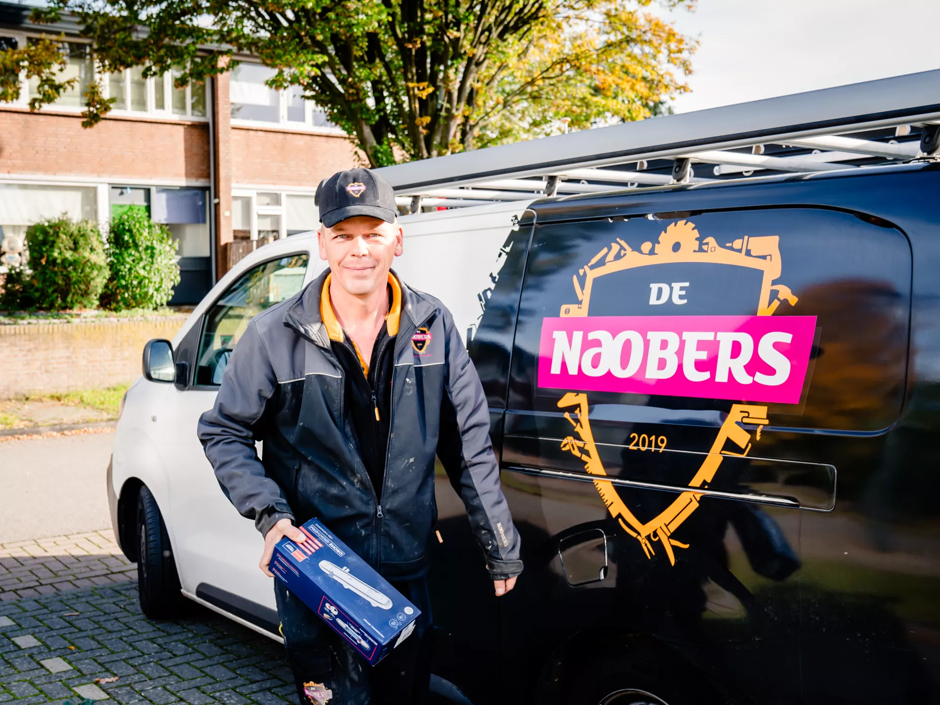Onderhoudsmonteur loopt weg van zijn klusbus met een doosje in zijn hand