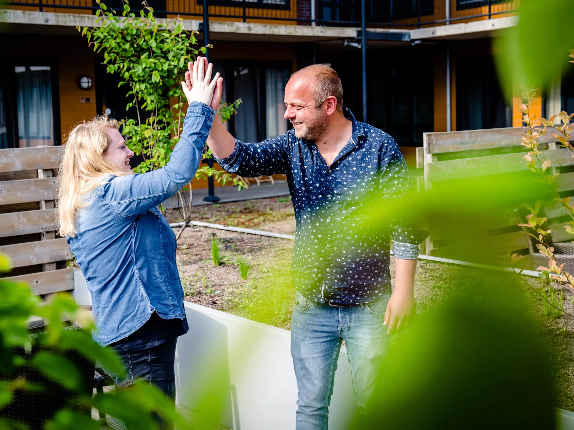 Een meneer en een mevrouw geven elkaar in een tuin een highfive