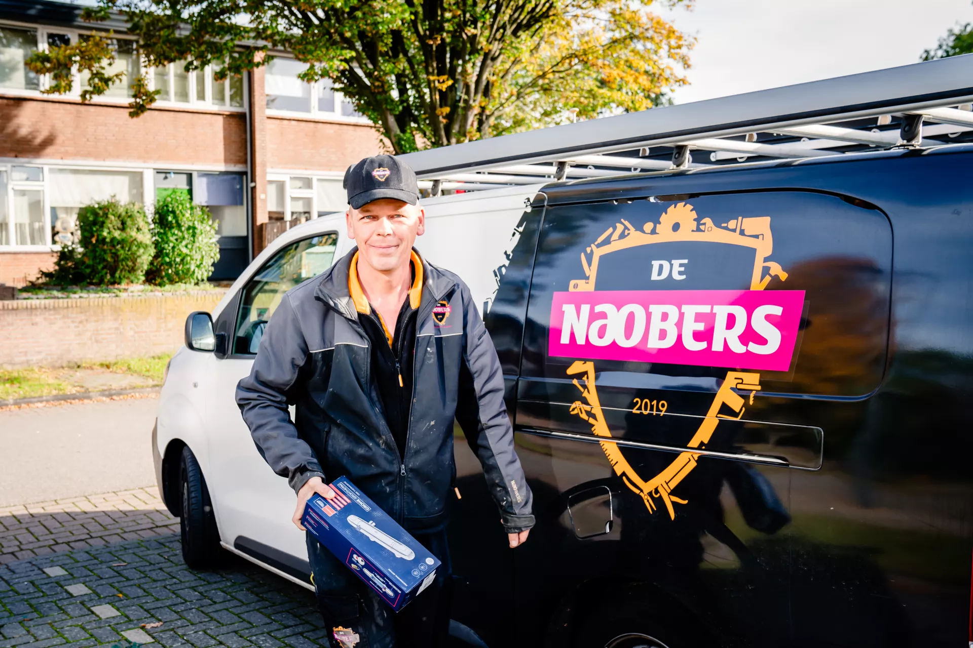 Onderhoudsmonteur loopt weg van zijn klusbus met een doosje in zijn hand