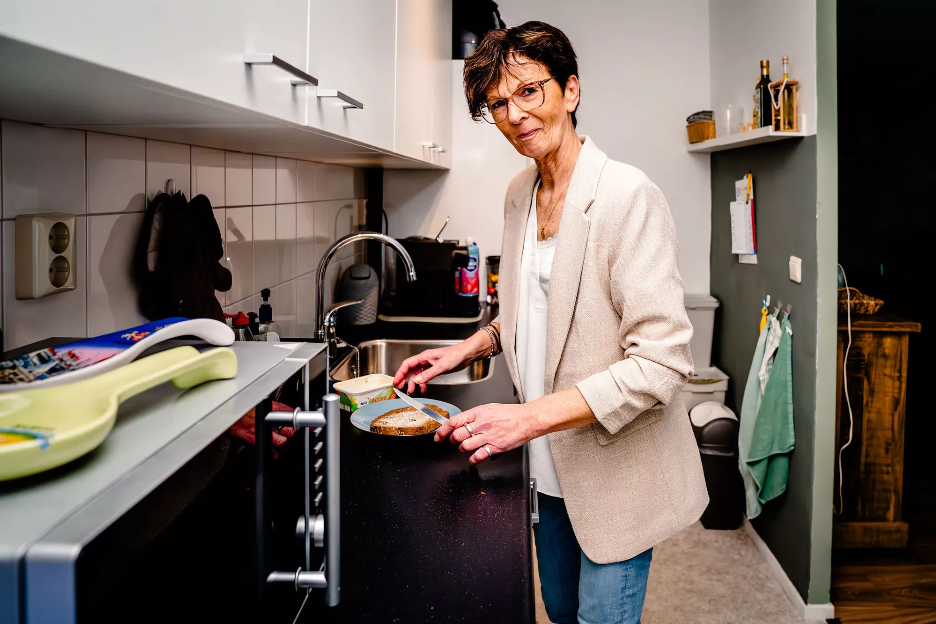 Dame smeert een boterham in haar keuken