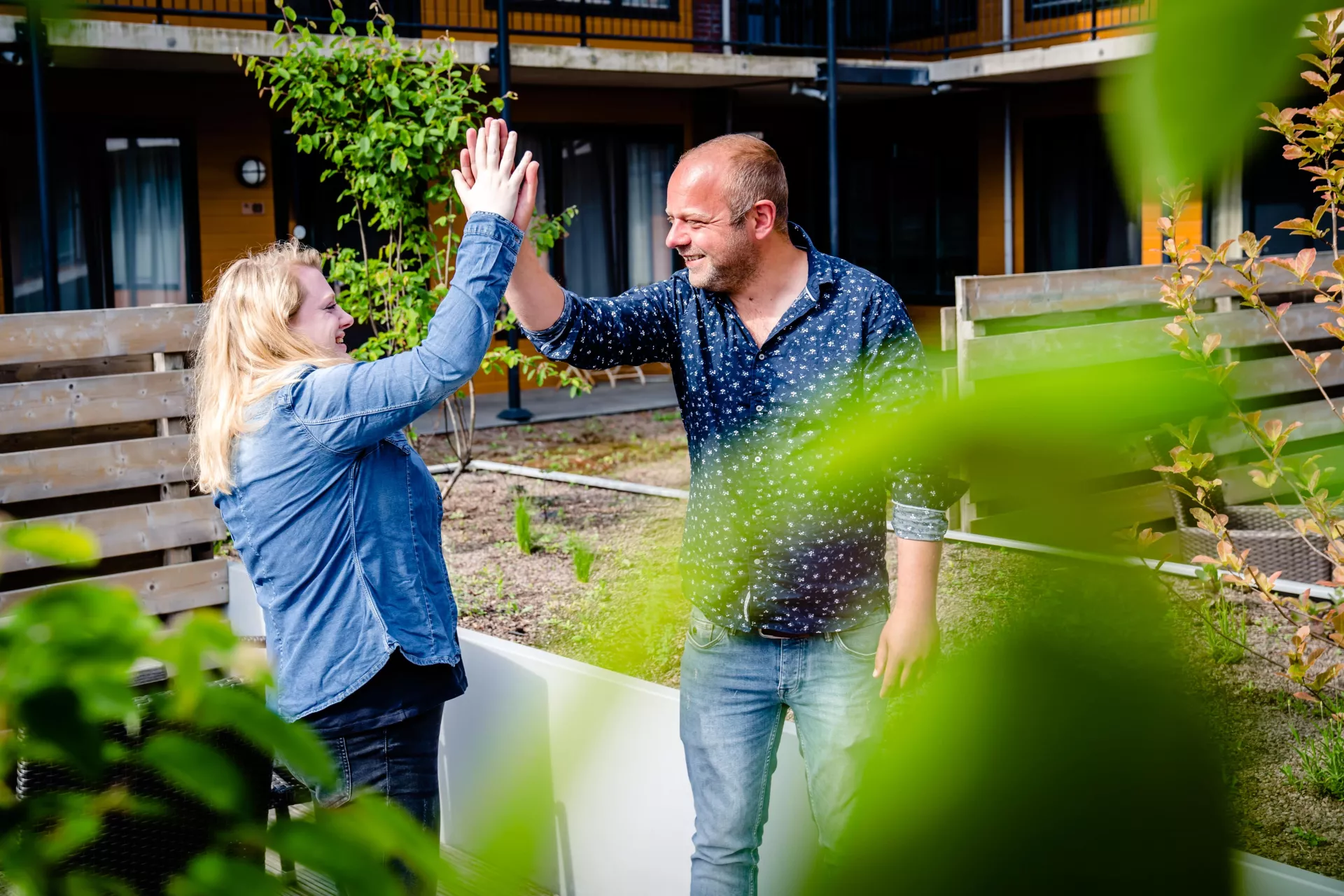 Een meneer en een mevrouw geven elkaar in een tuin een highfive