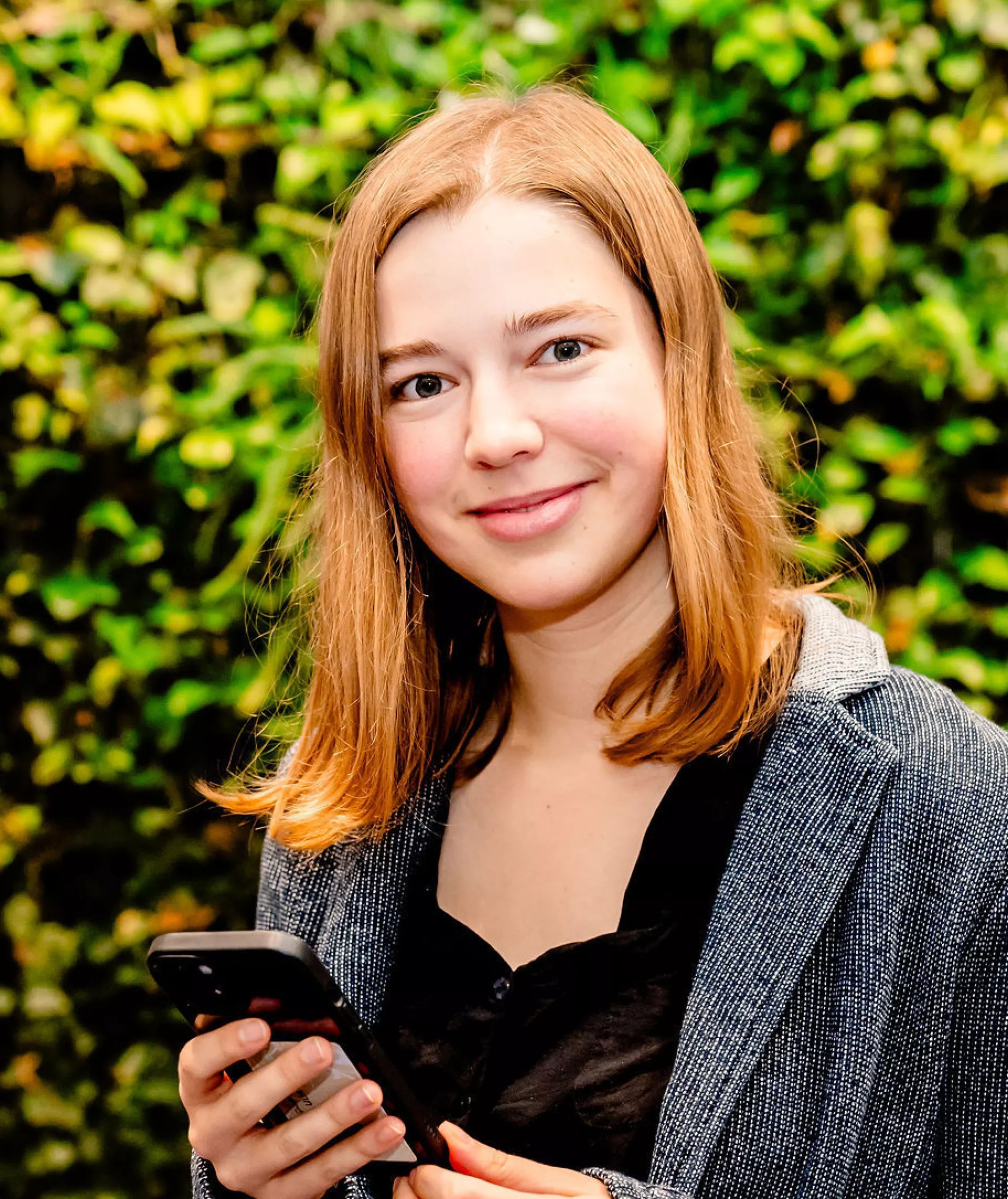 Dame met een mobiele telefoon in haar hand kijkt lachend