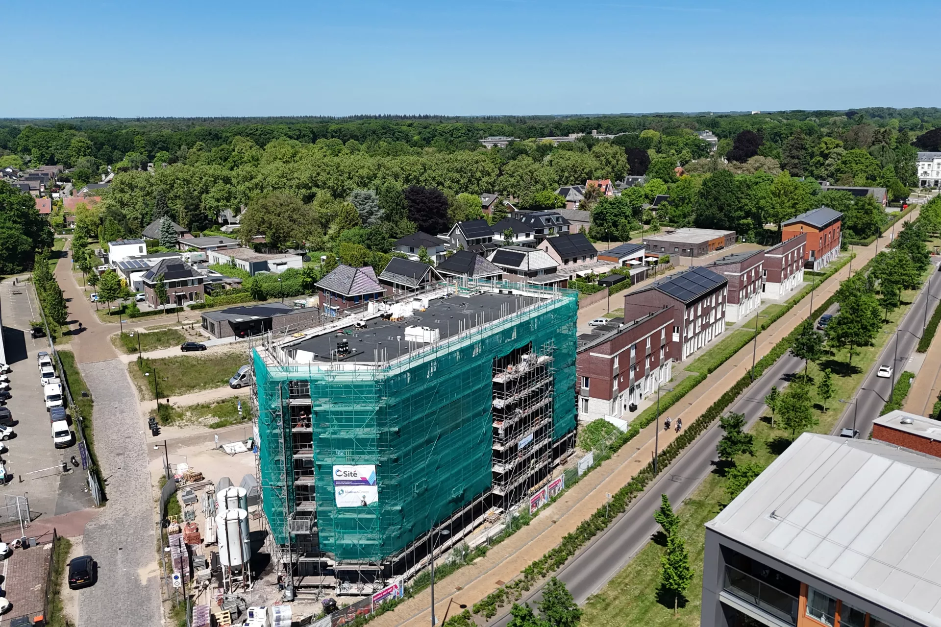 Bovenaanzicht van een appartementengebouw dat in de steigers staat met een groen bouwdoek er omheen